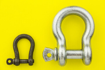 Large and small metal rigging shackles on yellow background. Professional rigging gear.