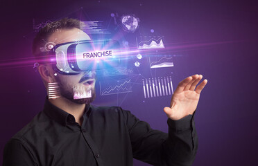 Fototapeta na wymiar Businessman looking through Virtual Reality glasses with FRANCHISE inscription, new business concept