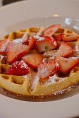 Buttermilk waffles with butter, maple syrup and crispy southern fried chicken. Classic American breakfast or brunch favorite. Made from scratch  waffles served with butter and maple syrup.