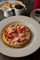 Buttermilk waffles with butter, maple syrup and crispy southern fried chicken. Classic American breakfast or brunch favorite. Made from scratch  waffles served with butter and maple syrup.