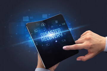 Businessman holding a foldable smartphone with DISASTER RECOVERY inscription, cyber security concept