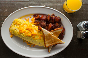 Omelette made with bacon, ham, sausage, bell peppers, heirloom tomatoes, spinach, onions, cheddar and Swiss cheese. Served with crispy potato hash, a classic American breakfast or brunch favorite.