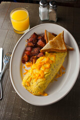 Omelette made with bacon, ham, sausage, bell peppers, heirloom tomatoes, spinach, onions, cheddar and Swiss cheese. Served with crispy potato hash, a classic American breakfast or brunch favorite.