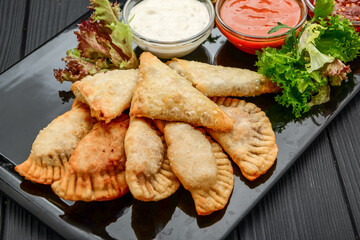 Fried turnovers or chebureki with a filling of ground beef meat and onion, spinach