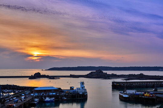Image of St Helier Harbour Pierheads at sunset with Elizabeth Castle and St Aubins Bay. Jersey CI
