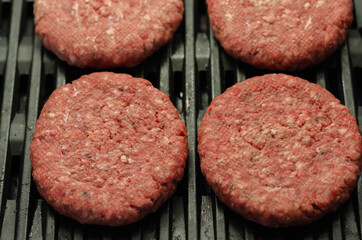 Seasoned beef burgers with a pinch of salt and black pepper on the grill