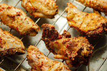 Raw chicken wings with a rendang style rub made with chilli and garlic on the grill tray