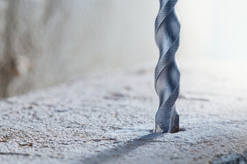 metal drill bit make holes in concrete wall on industrial drilling machine with shavings. Metal...