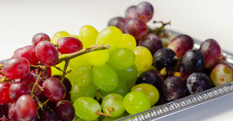 Three types of green, red and black grapes on a silver tray