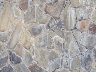 Exterior gray piebald wall with decorative masonry of many pieces of various shapes and sizes