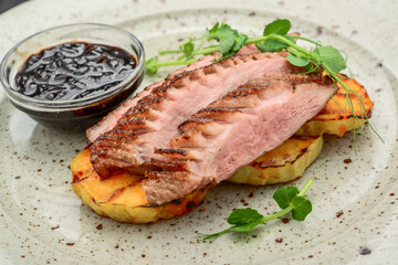 Juicy duck breast steaks with caramelized apple on plate. Hot Meat Dishes