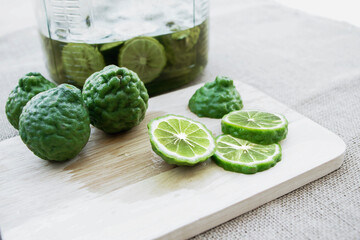 Bergamot fruit cutting slices on wooden clipping board on sackcloth background. Bergamot material of essential oils for beauty and cooking food ingredient healthy.