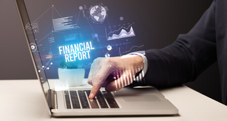 Fototapeta premium Businessman working on laptop with FINANCIAL REPORT inscription, new business concept