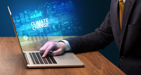 Businessman working on laptop with CLIMATE CHANGE inscription, cyber technology concept