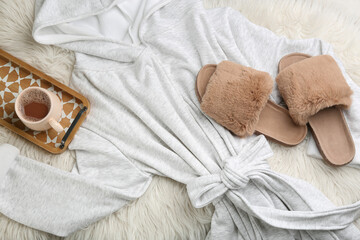 Pair of fluffy slippers, bath robe and coffee on fuzzy carpet, flat lay. Comfortable home outfit