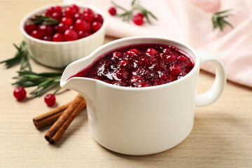 Cranberry sauce in pitcher on wooden table