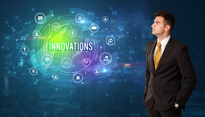 Businessman thinking in front of technology related icons and INNOVATIONS inscription, modern technology concept