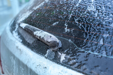 Car window and windscreen wiper in ice after freezing rain. Freezing rain, anomalies of nature. Soft focus technique