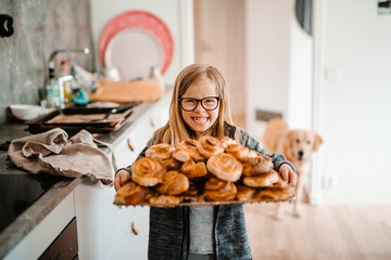 Smiling girl holding tray with cinnamon buns