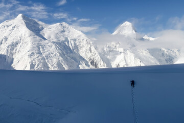 Mountain climber climb snow wall in front of Khan Tengri peak (7010 m), Central Tian Shan, China - Kyrgyzstan - Kazakhstan.