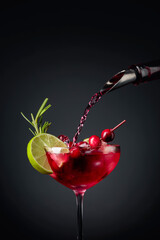 Cranberry cocktail garnished with berries, lime, and rosemary.