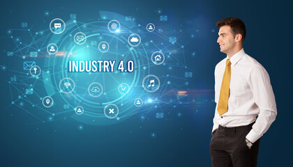 Businessman thinking in front of technology related icons and INDUSTRY 4.0 inscription, modern technology concept