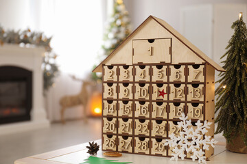 Wooden house shaped Advent calendar in room decorated for New Year