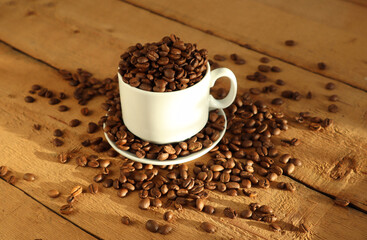 Coffee beans in a white cup on a wooden surface.