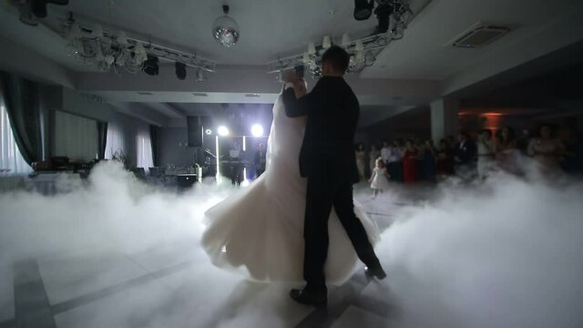 Dance of brides at the wedding. Heavy smoke that is highlighted with white light. The first dance of the newlyweds at the wedding