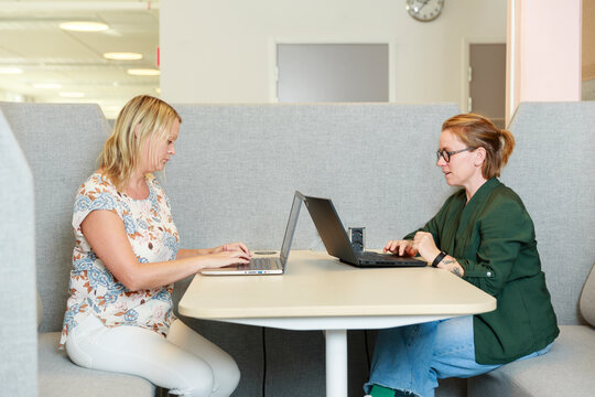 Coworkers using laptops at work