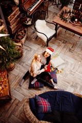 top view. Two woman lying on the floor by fireplace with New Year's decoration.