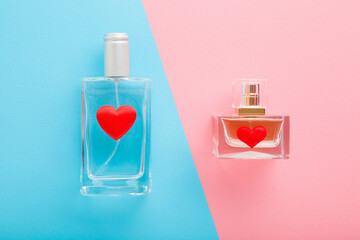 Male and female perfume bottles with bright red heart shapes on blue pink table background. Pastel colors. Closeup. Top down view.