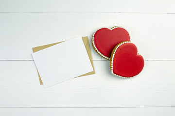 Blank greeting card mockup with paper envelope and red heart on white wooden table