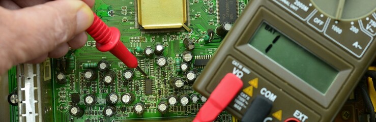 Mano reparando una placa de circuito impreso, placa electrónica