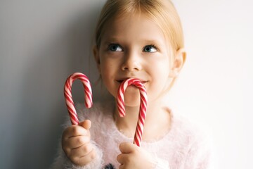 Little smiling girl eating new years candies, red Christmas candy. Close up portrait of a little child. New year concept. 2021. - 398767378