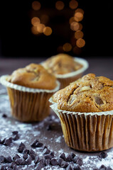 close up of delicious hand-made muffins decorated with a star-shaped pear, sugar and chocolate pear in festive atmosphere and colored lights.
