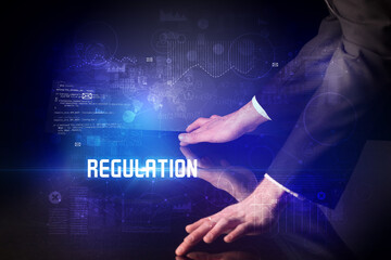 Hand touching digital table with REGULATION inscription, new age security concept
