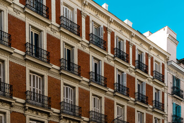 Fototapeta na wymiar Old residential building with brick facade and iron balconies in Madrid