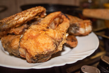 Ready ruddy carp in breading on a white plate on the cooking surface 