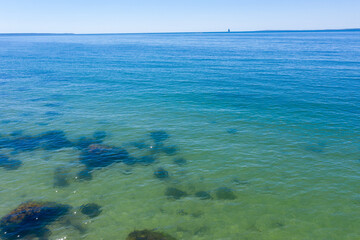 Blue green ocean with sailboat on horizon