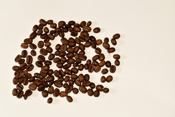 Roasted coffee beans are scattered on a white sheet