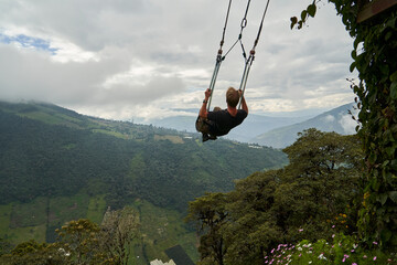 young blond haired caucasian man sitting on a large wooden swing at the tree house, casa del arbol,...
