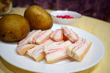 Pork fat with boiled potatoes in a uniform.