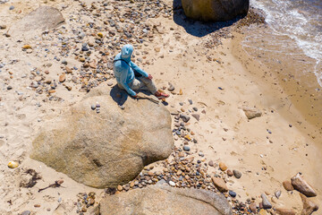 woman with stick facing away from camera on beach