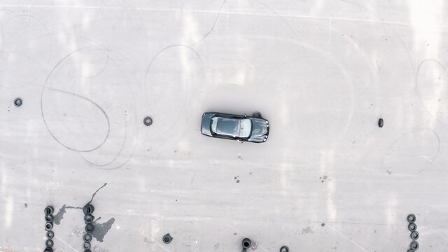 practical driving test. student on a black car bypasses obstacles. slalom by car between tires. aerial view. driving training area, driving course. Driving lessons training. top shot