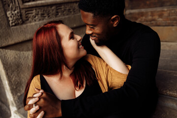 Adorable couple cuddling near the house, walking at the city, charming African American husband gently hug beautiful wife, overjoyed woman smiling, tender moments concept