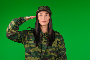 Fototapeta premium Portrait of a woman in military uniform. Holds hand to temple. Military greeting. Green background.