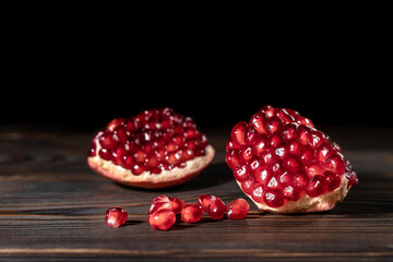 Craked ripe pomegranate on dark wooden background