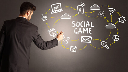businessman drawing social media icons with SOCIAL GAME inscription, new media concept