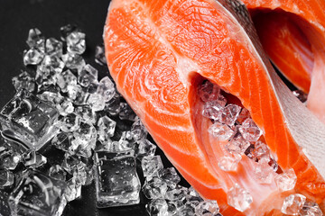 salmon sliced into pieces on a black stone board with ice cubes. red fish. fresh trout for cooking.
